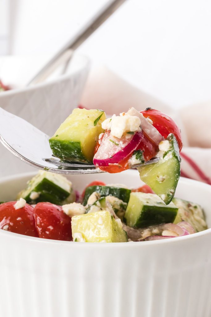 A bite of an easy cucumber salad with tomatoes, onion and feta.