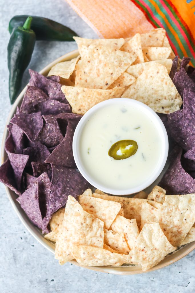 A plate of chips and dip made with white cheese.