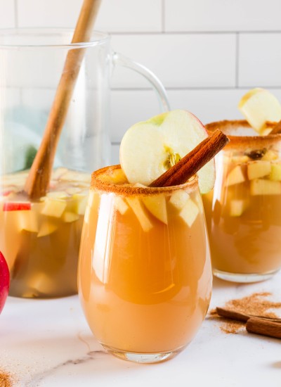 A glass of apple sangria with a cinnamon stick.