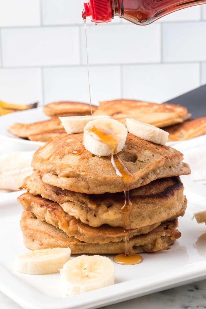 Pancakes covered in syrup and bananas.