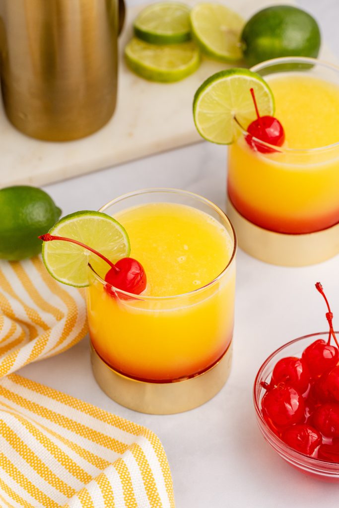 Cherries and lime slices garnish a tropical cocktail.