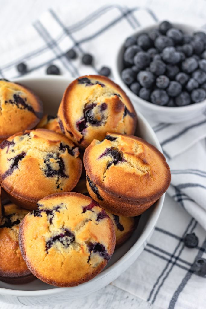 A bowl of muffins with fresh blueberries inside.