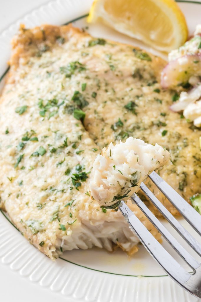 A bite of tilapia coated in herbs and Parmesan cheese.