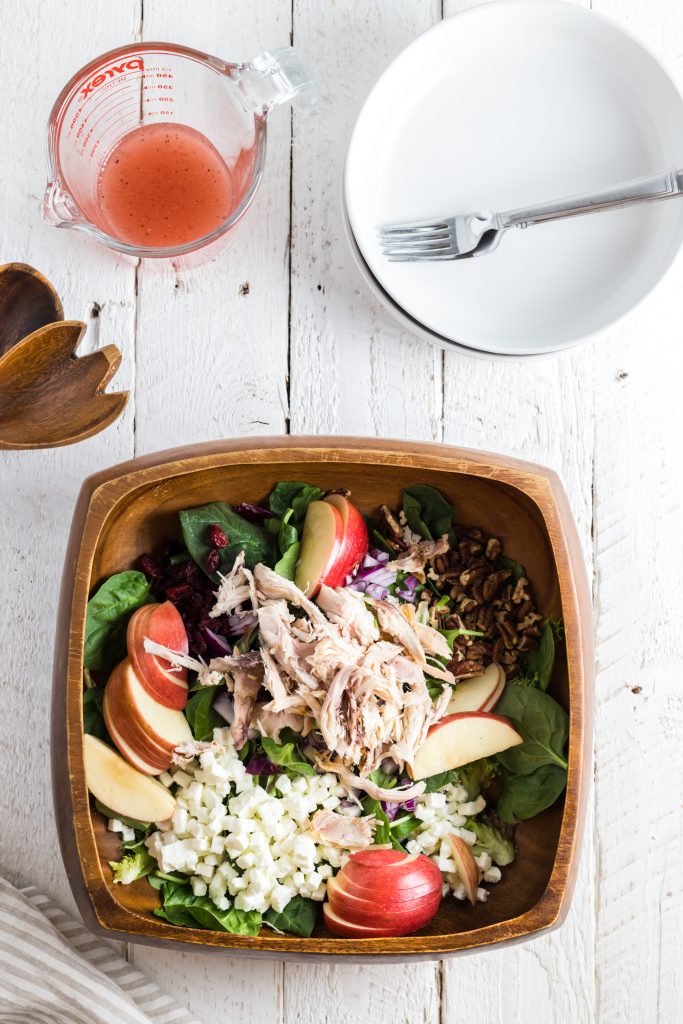 A salad with sliced apple and chicken in a bowl.