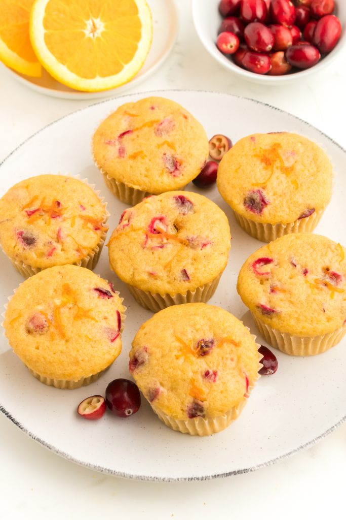 Orange muffins with cranberries on a plate.